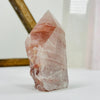 Hematoid Semi Polished Crystal Point AS IS on white surface with display in background.
