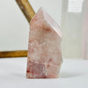 Hematoid Semi Polished Crystal Point AS IS on white surface with display in background.