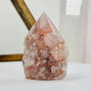 Hematoid Semi Polished Crystal Point AS IS on white surface with display in background.