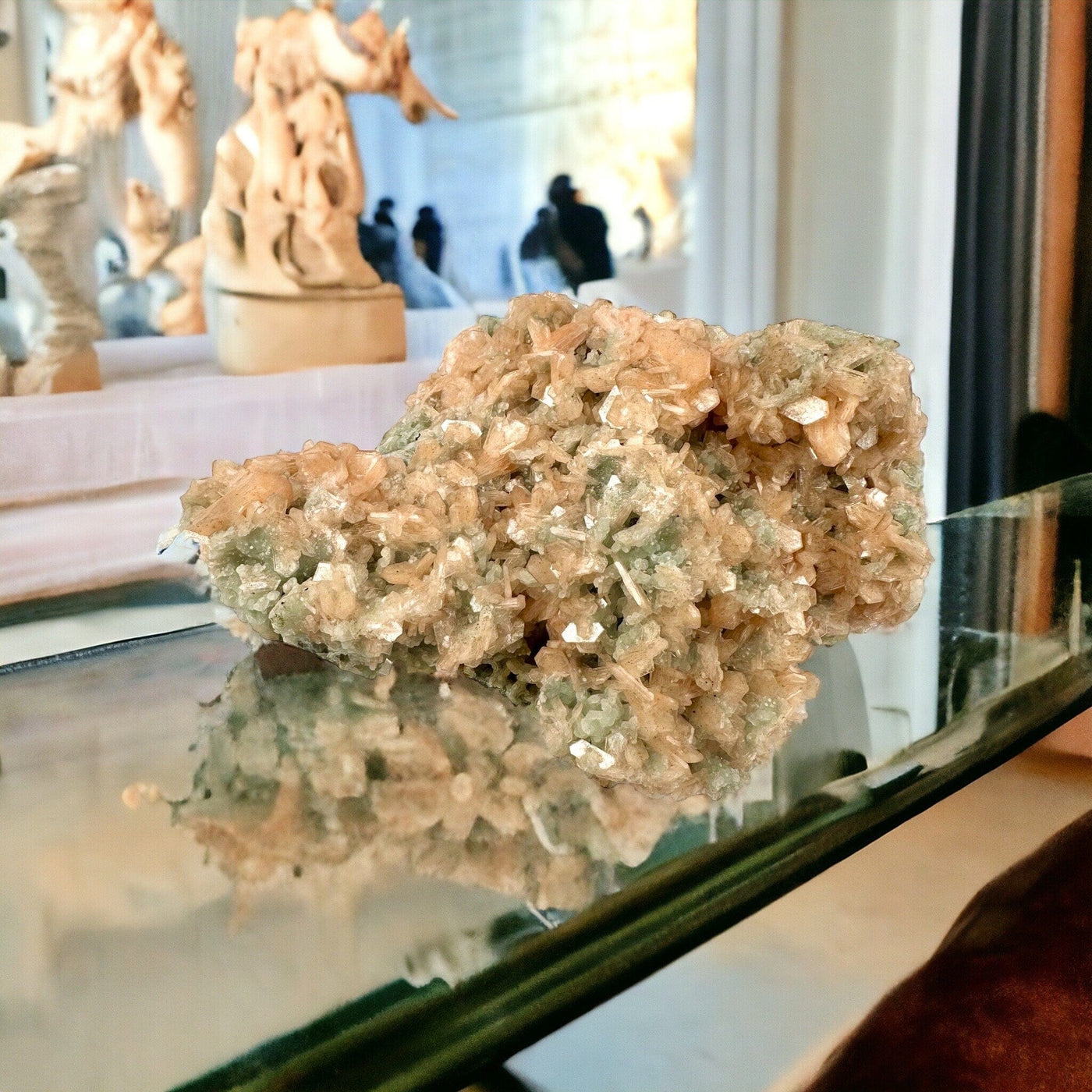 Peach Stilbite Cluster with Apophyllite and Zeolite - Museum Quality on a glass surface with marble statues in the background
