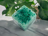 Large Green Crystal Fluorite Cube on marble table for reference.