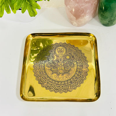 close up of the engraved moth with sun and moon on this brass tray 