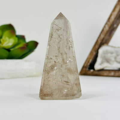 Smokey Quartz obelisk with decorations in the background
