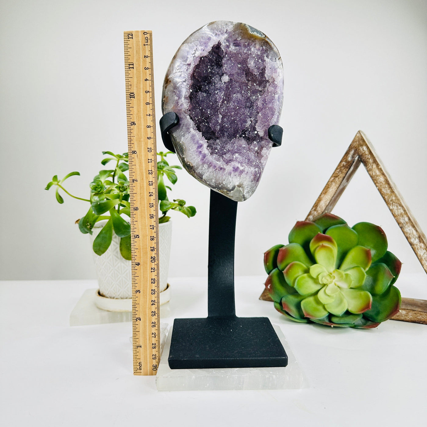 amethyst geode on stand next to a ruler for size reference