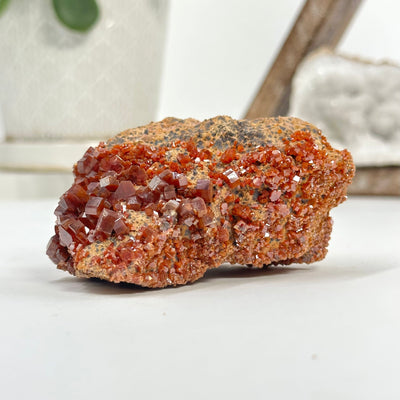 Natural vanadinite freeform with decorations in the background
