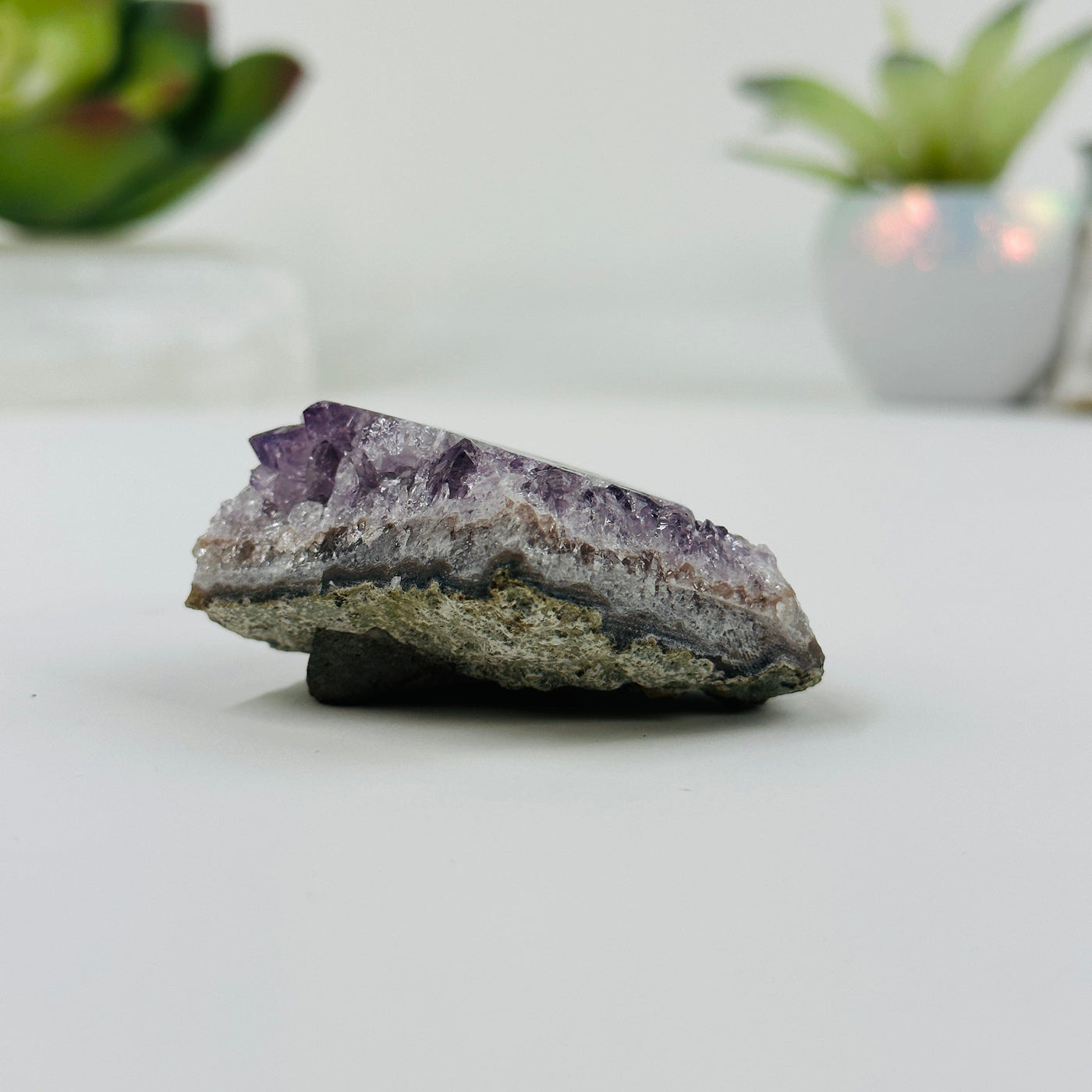 side view of amethyst stalactite cluster with decorations in the background