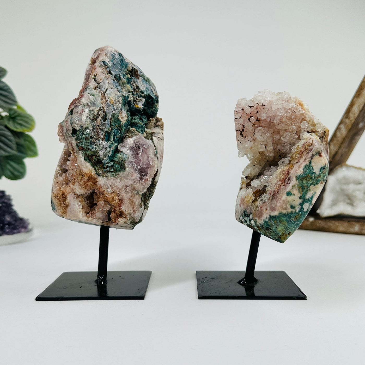 side view of 2 Pink amethyst on metal stands with decorations in the background