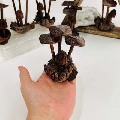 hand holding up dark wooden mushrooms with decorations