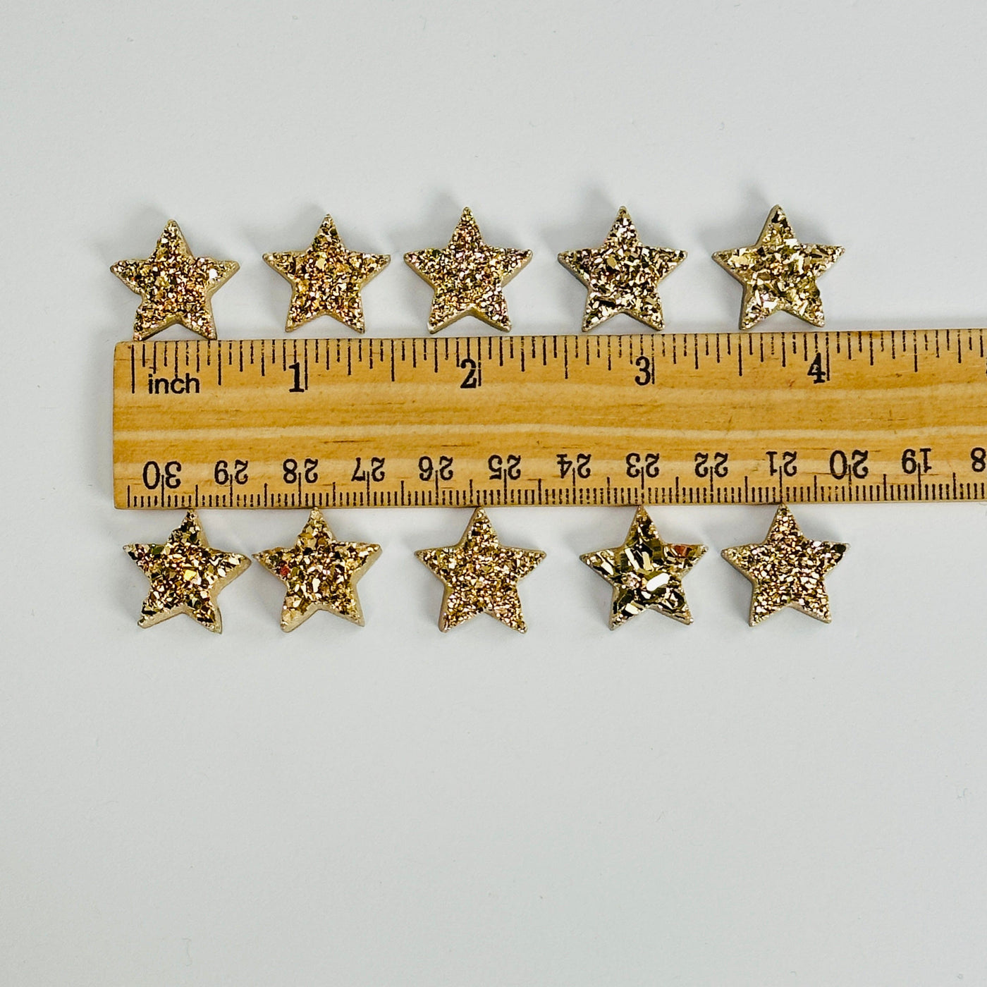 gold titanium druzy star cabochons next to a ruler for size reference