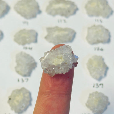 finger holding up crystal stalactite slice