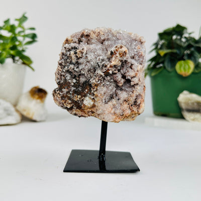 raw pink amethyst on metal stand with decorations in the background
