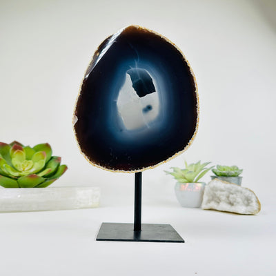 Natural Dark Agate with Druzy Center on Metal Stand with decorations in the background