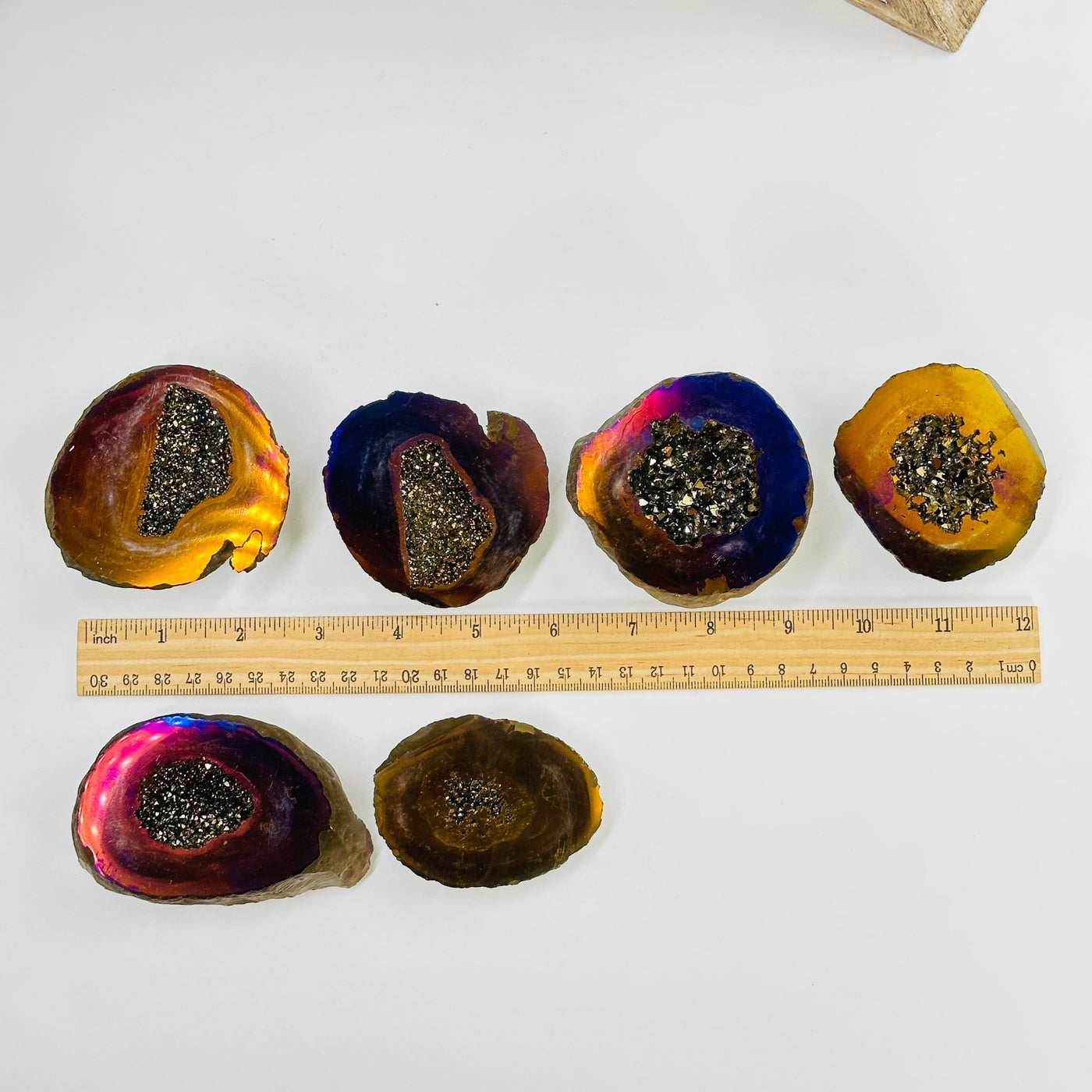 rainbow and gold titanium coated geode boxes next to a ruler for size reference