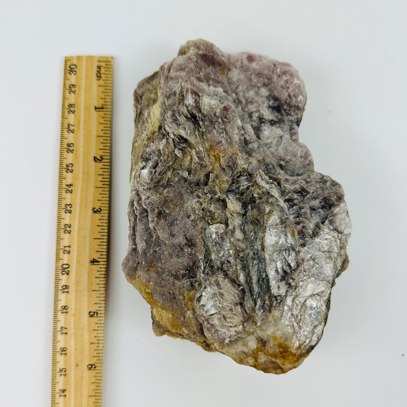 lepidolite mica next to a ruler for size reference