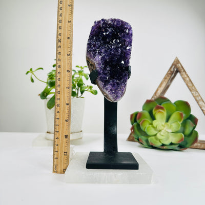 semi polished amethyst on stand next to a ruler for size reference