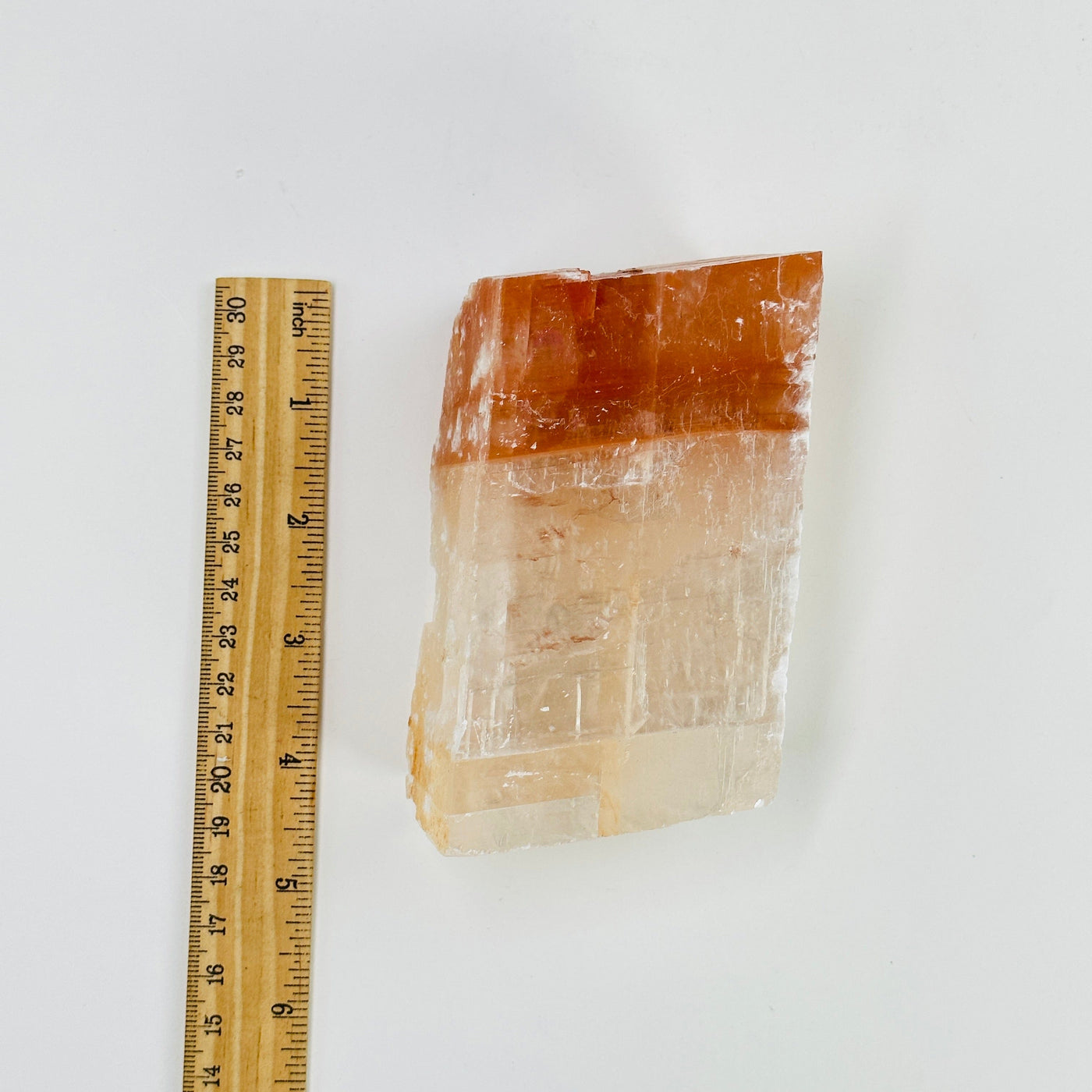 pink optical calcite next to a ruler for size reference