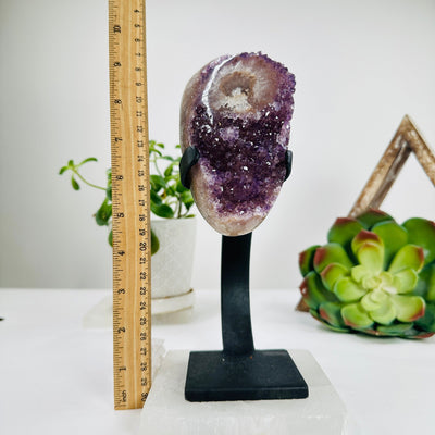polished amethyst on stand next to a ruler for size reference