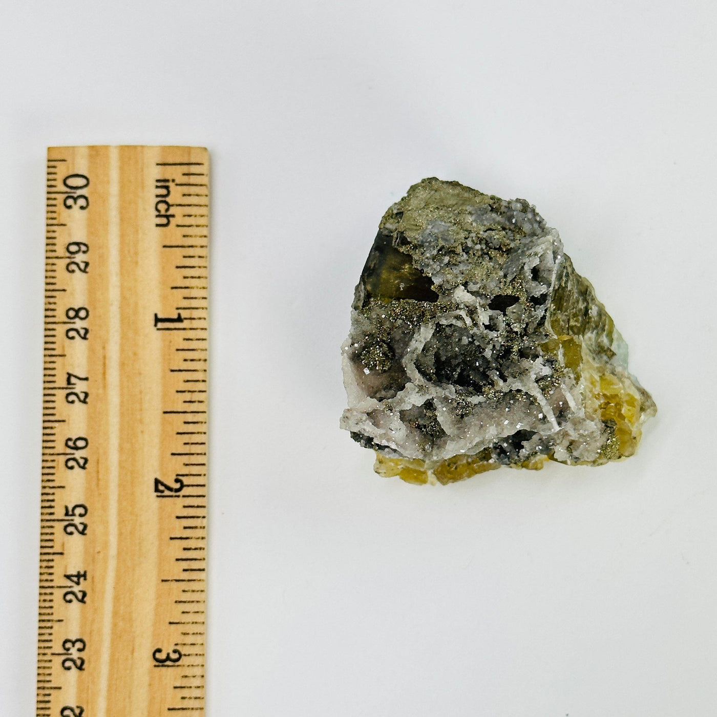 epidote with pyrite growth next to a ruler for size reference