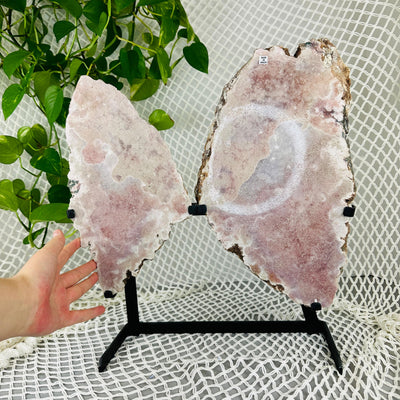 hand next to Pink amethyst wings with decorations in the background