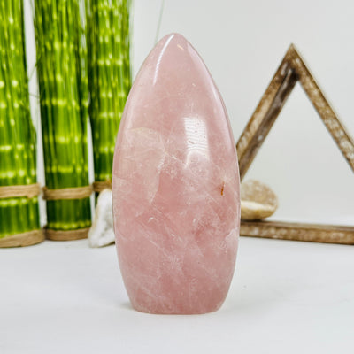 backside of rose quartz polished cutbase with decorations in the background