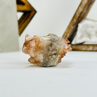 side view of tangerine quartz cluster with decorations in the background