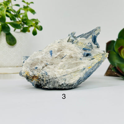 blue kyanite on matrix with decorations in the background