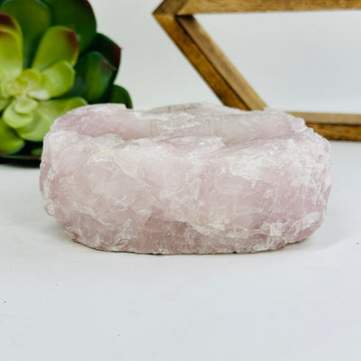 side view of rose quartz candle holder with decorations in the background