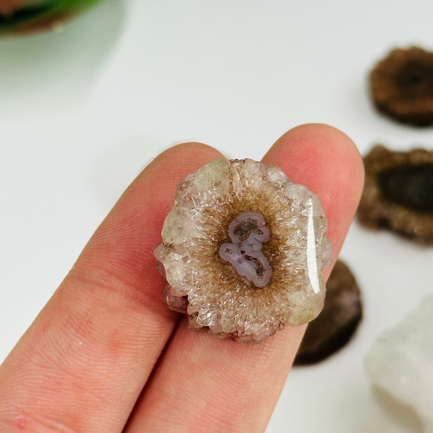 2 fingers holding up amethyst stalactite slice for size reference