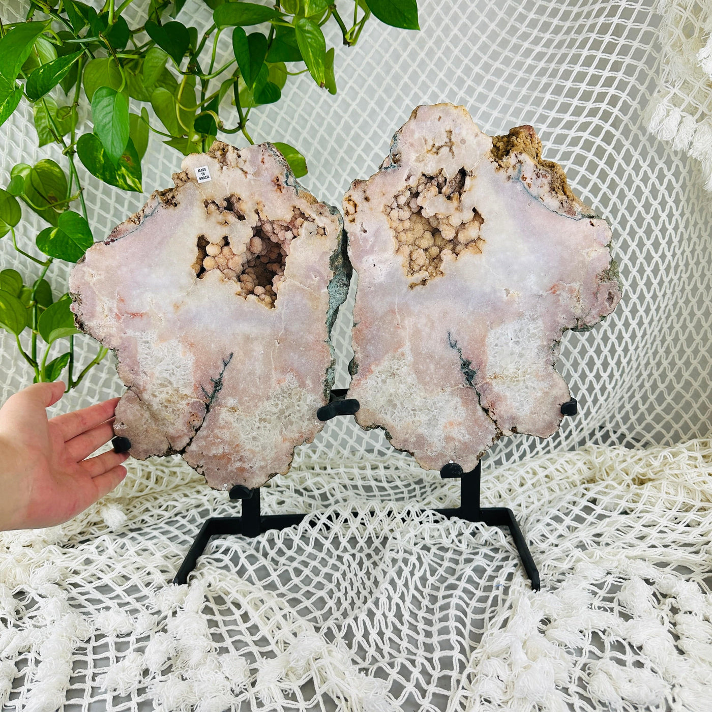 hand next to Pink amethyst wings on metal stand with decorations in the background