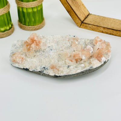 Peach Apophyllite on matrix with decorations in the background