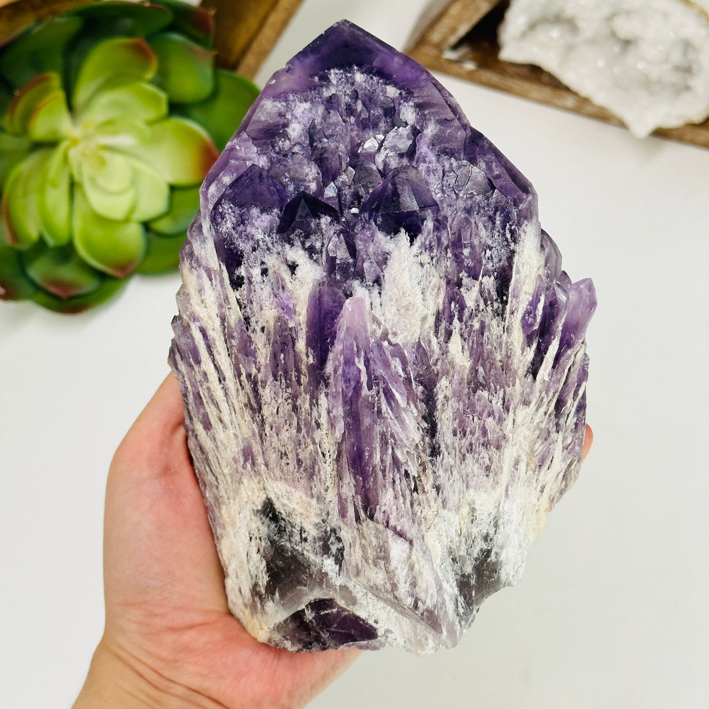 hand holding up amethyst cluster with decorations in the background