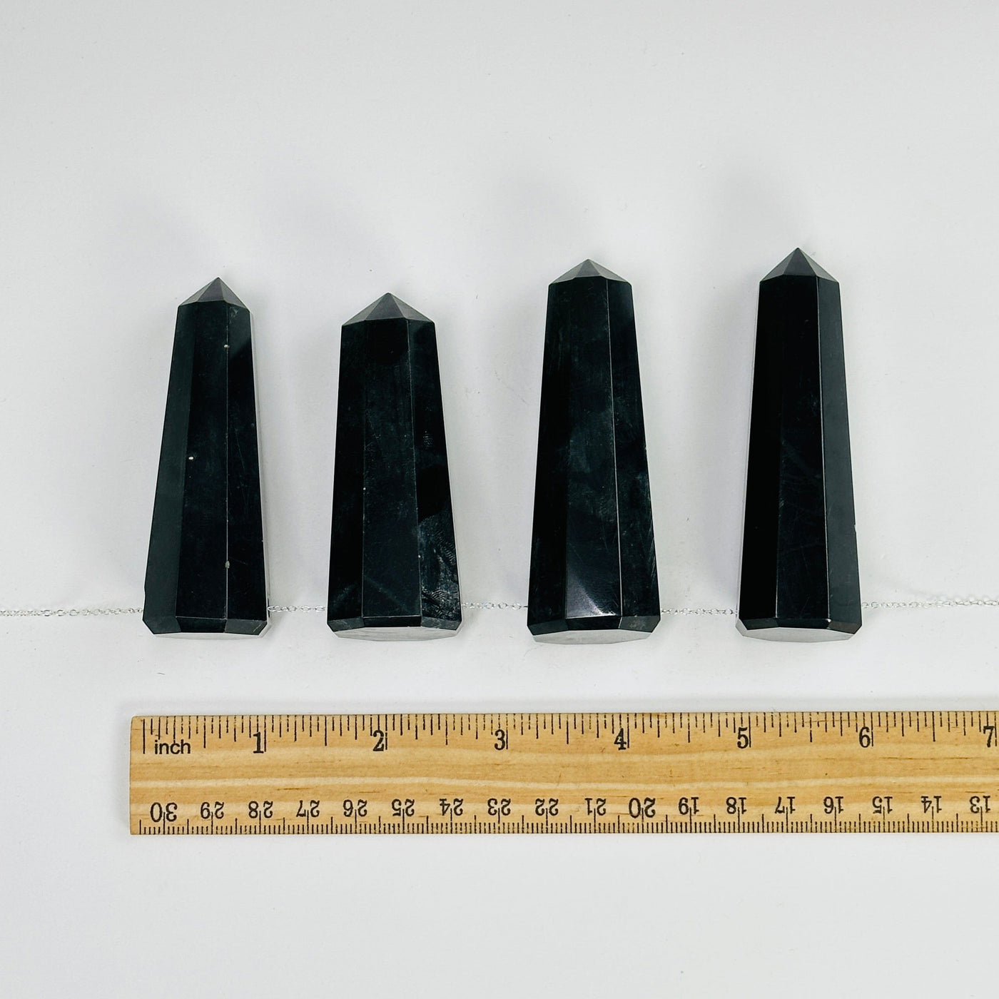 onyx obelisk points with a chain through them next to a ruler for size reference