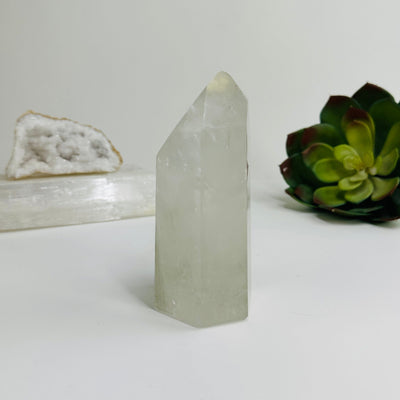 side view of Crystal quartz polished point with decorations in the background