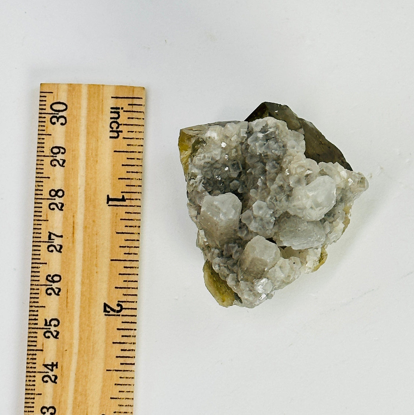 epidote with crystal quartz growth cluster next to a ruler for size reference