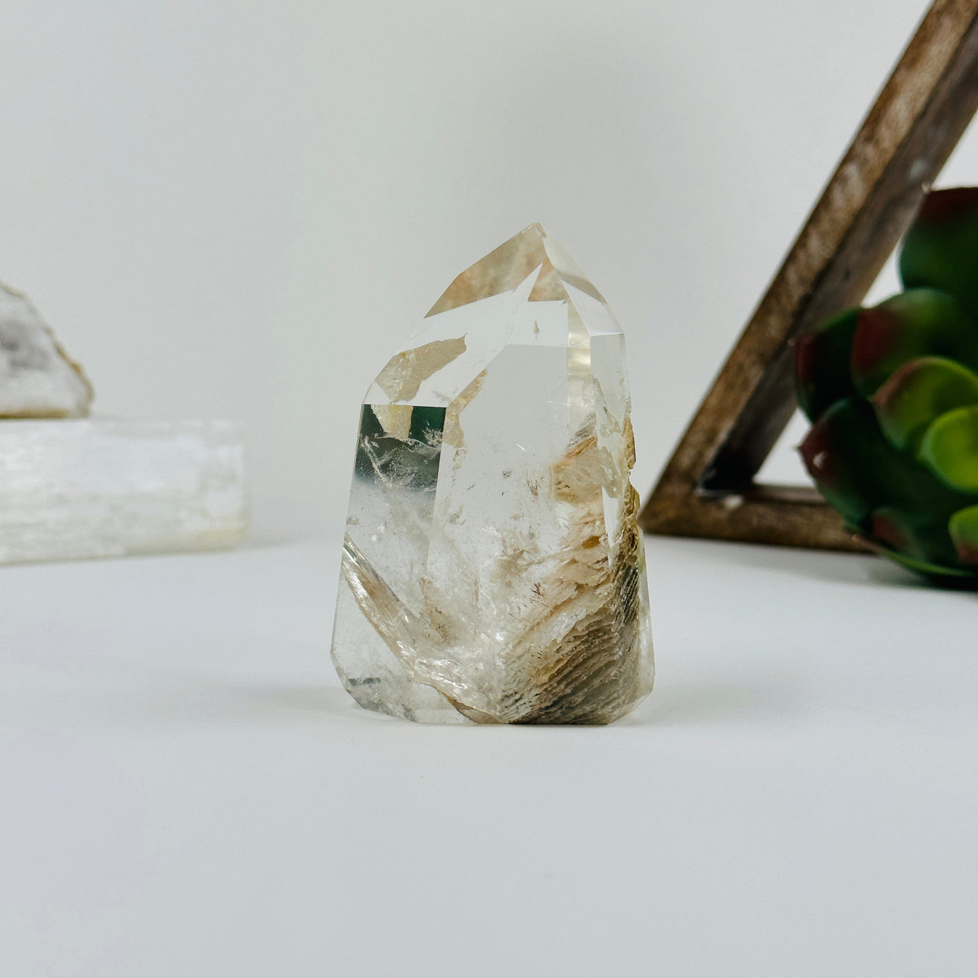 Polished lodalite point with decorations in the background