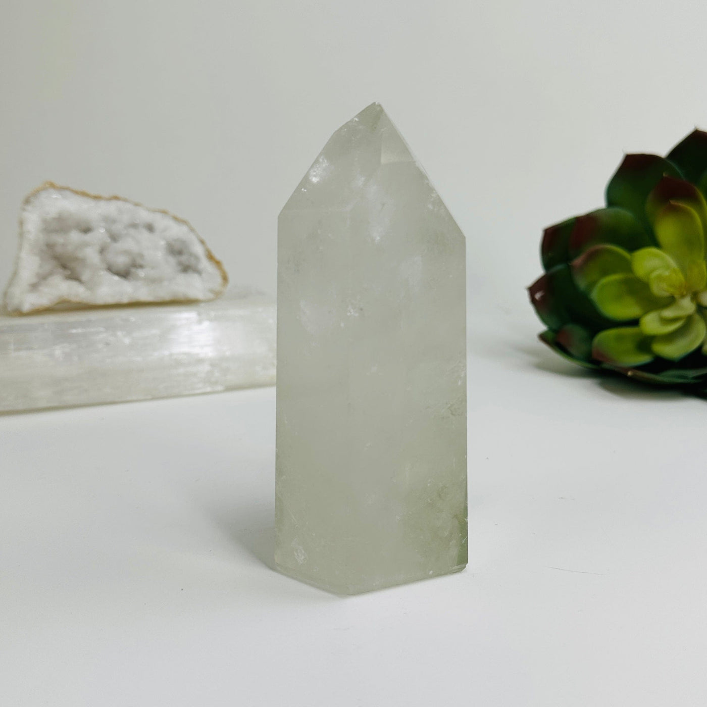 Crystal quartz polished point with decorations in the background