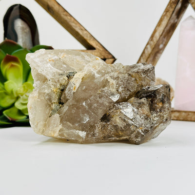 smokey quartz cluster with decorations in the background
