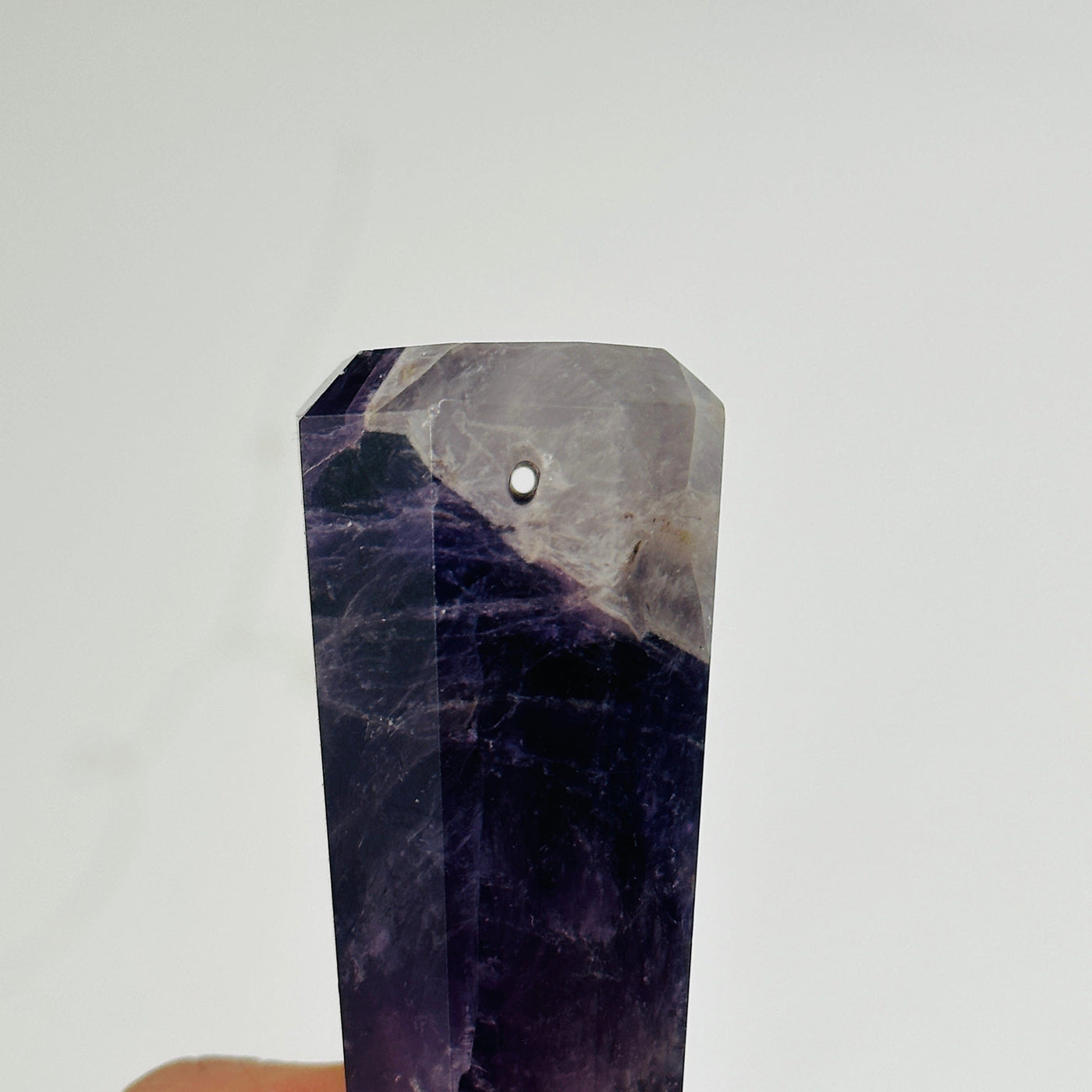 up close shot of hole in amethyst obelisk point on white background