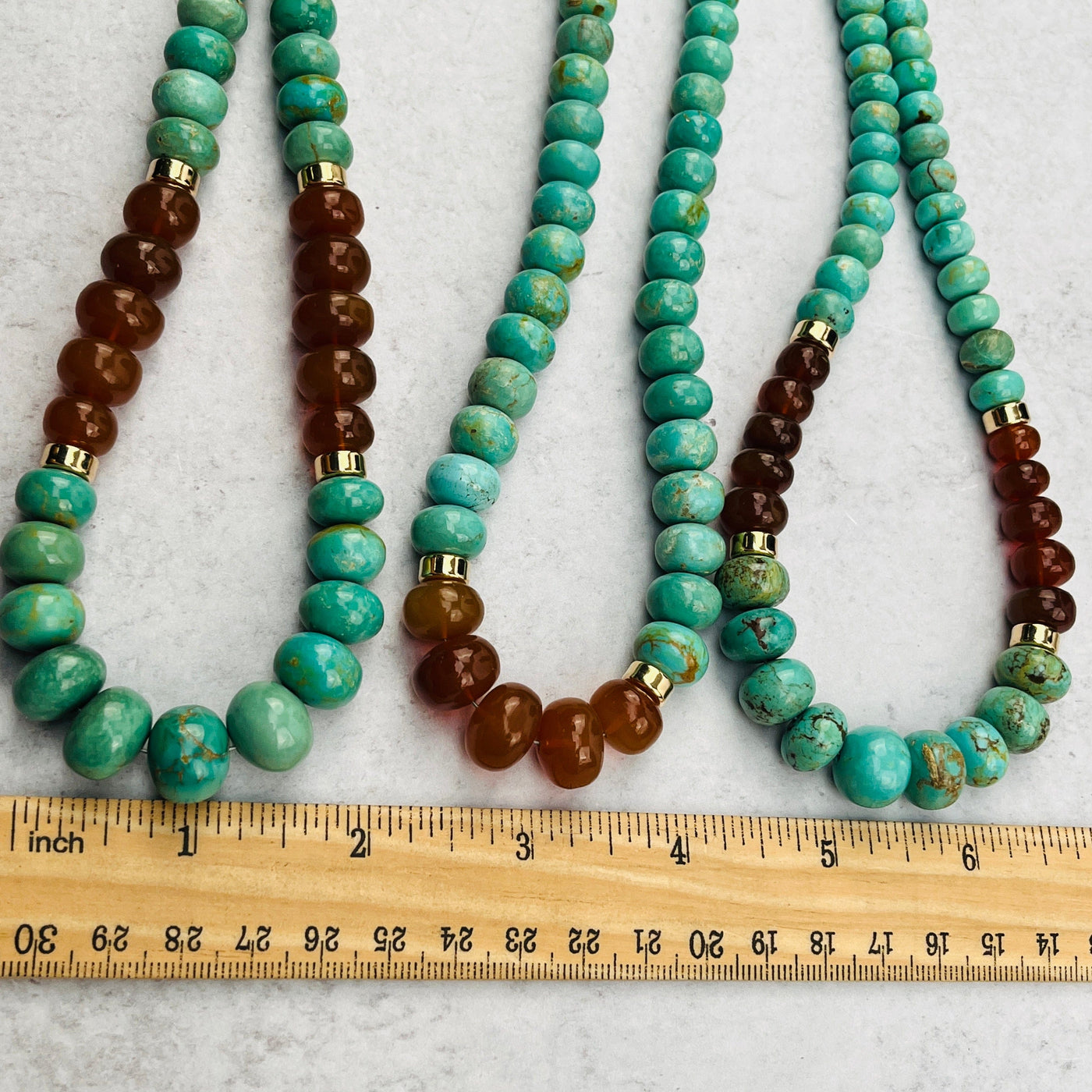close up of the necklace beads next to a ruler for size reference 