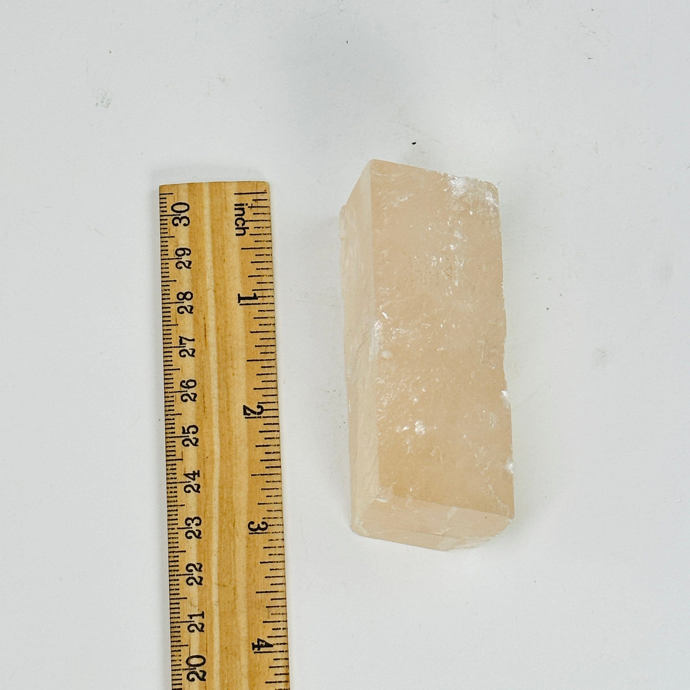 pink optical calcite next to a ruler for size reference