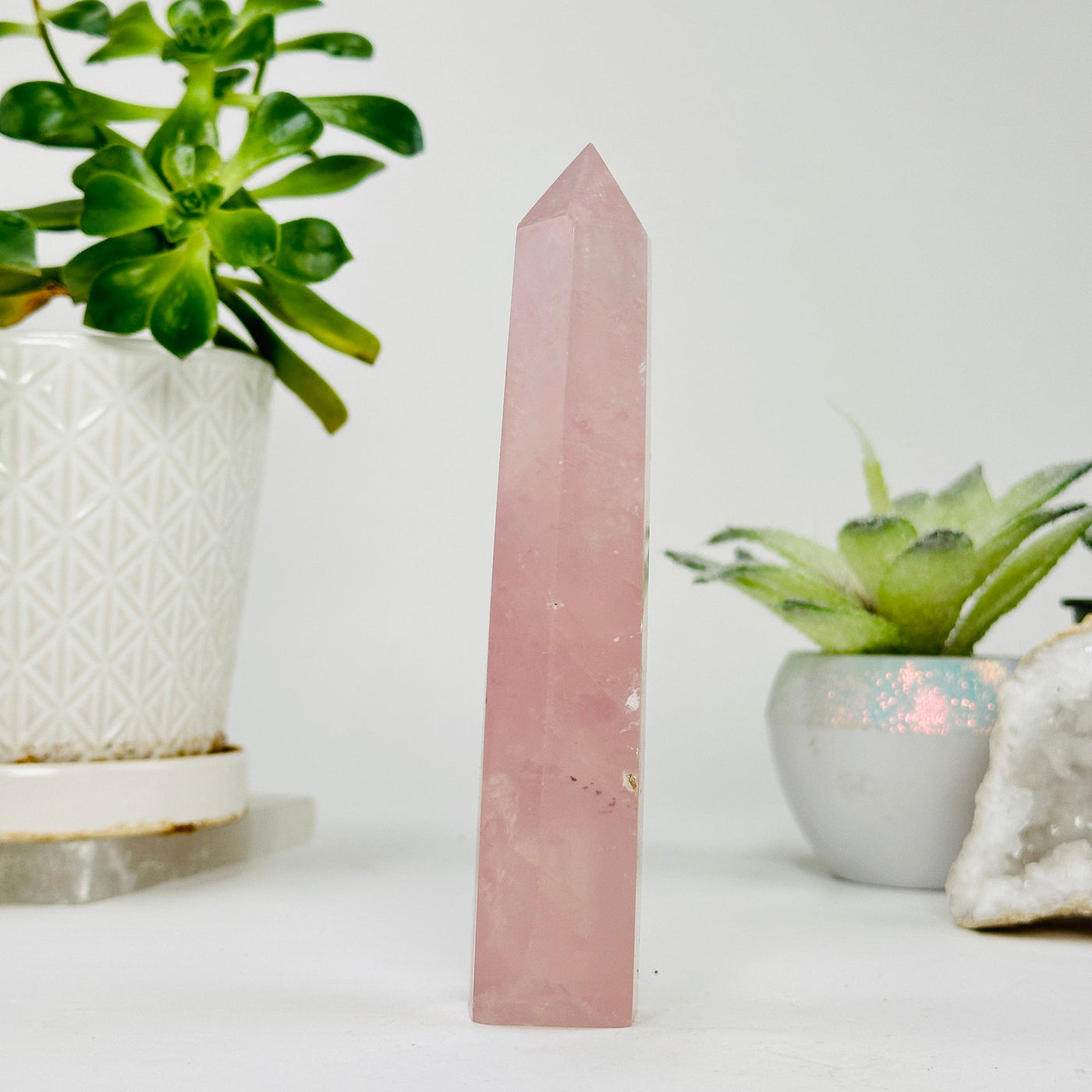 side view of rose quartz polished point with decorations in the background