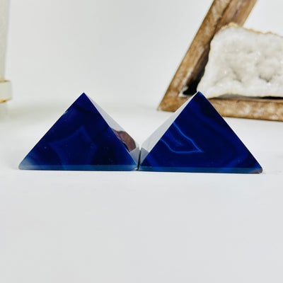 side view of Purple dyed agate pyramid with decorations in the background