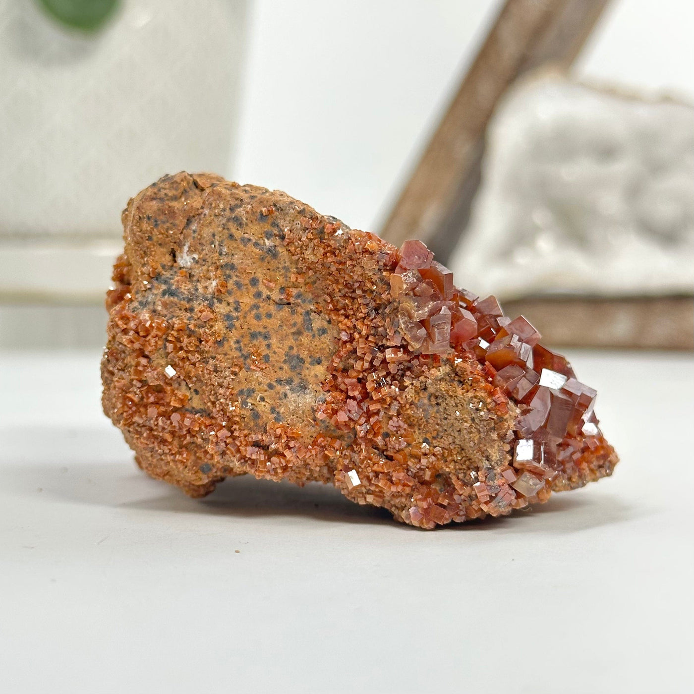side view of Natural vanadinite freeform with decorations in the background