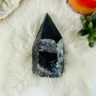 top view of smokey quartz semi polished point with decorations in the background