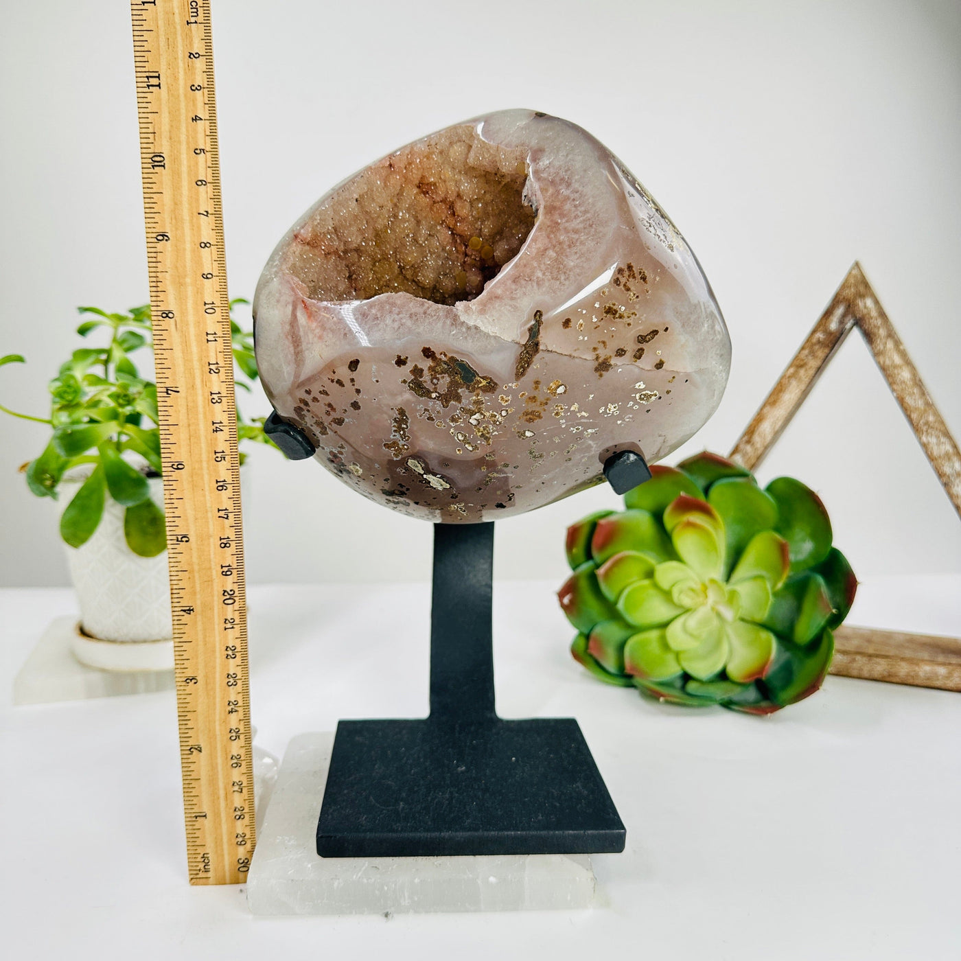 amethyst geode on stand next to a ruler for size reference