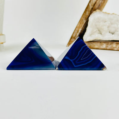 side view of Purple dyed agate pyramid with decorations in the background