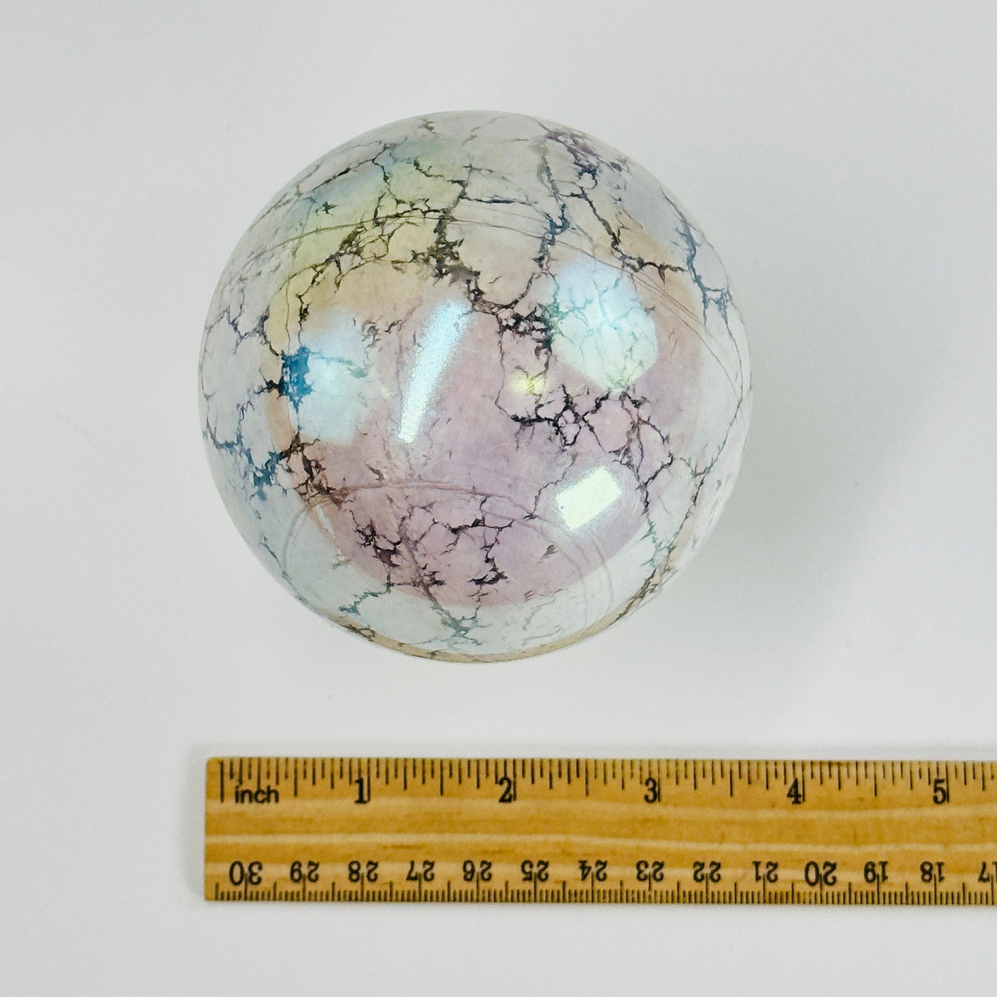 aura howlite sphere next to a ruler for size reference