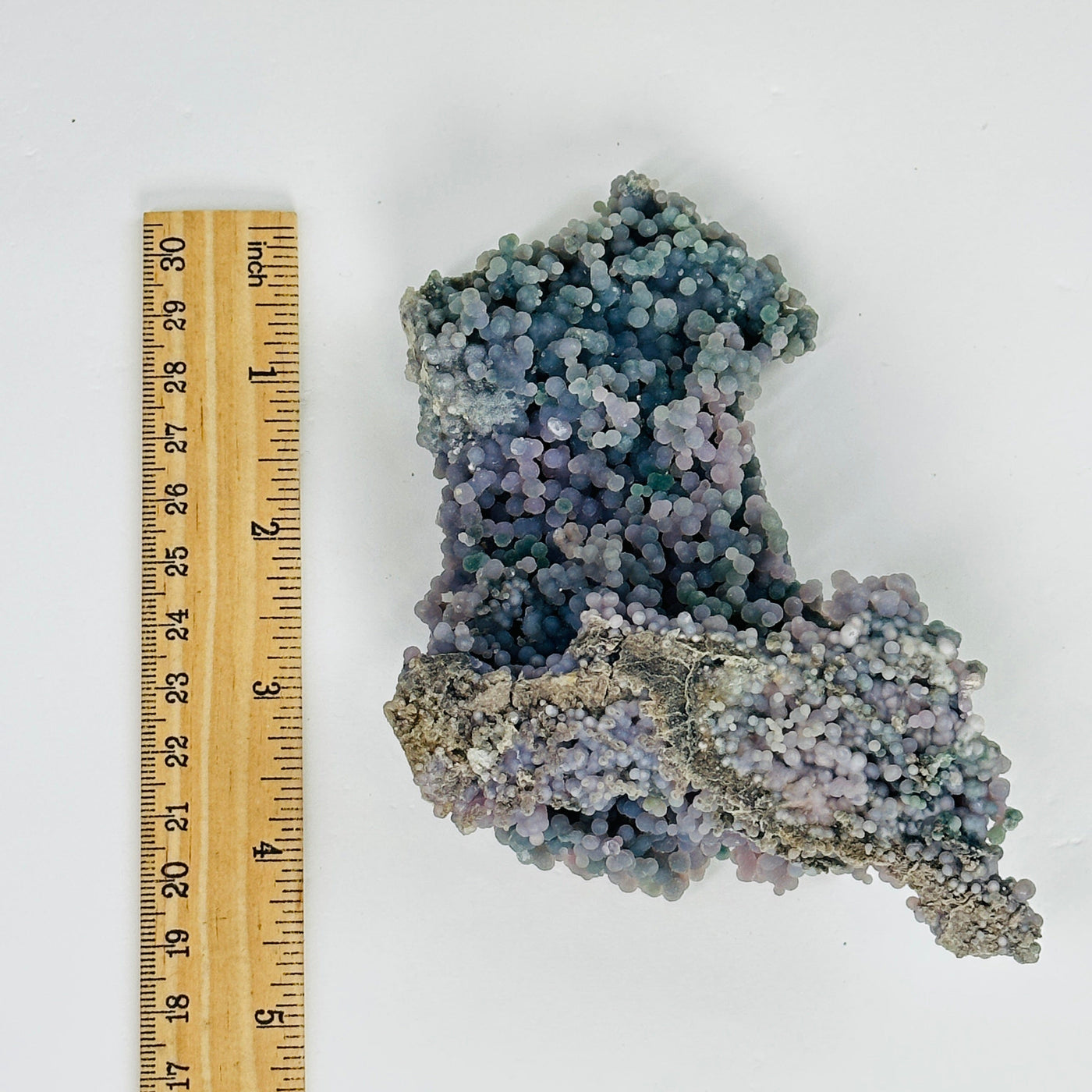 grape agate cluster next to a ruler for size reference