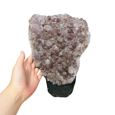 hand next to amethyst decoration for size reference