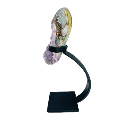 side view of amethyst geode on stand on white background
